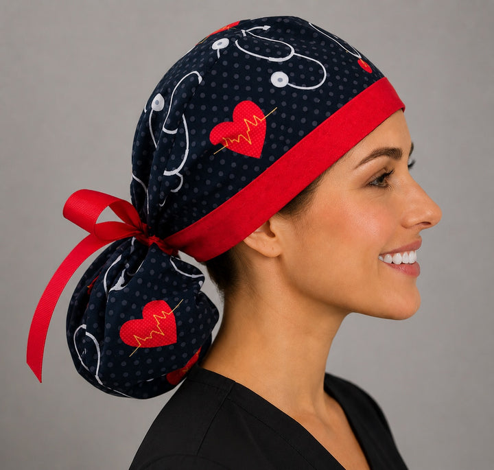 Heartbeat EKG cardiology ponytail surgical cap right side profile showing gathered ponytail pouch of red hearts and stethoscopes on black with red ribbon tie