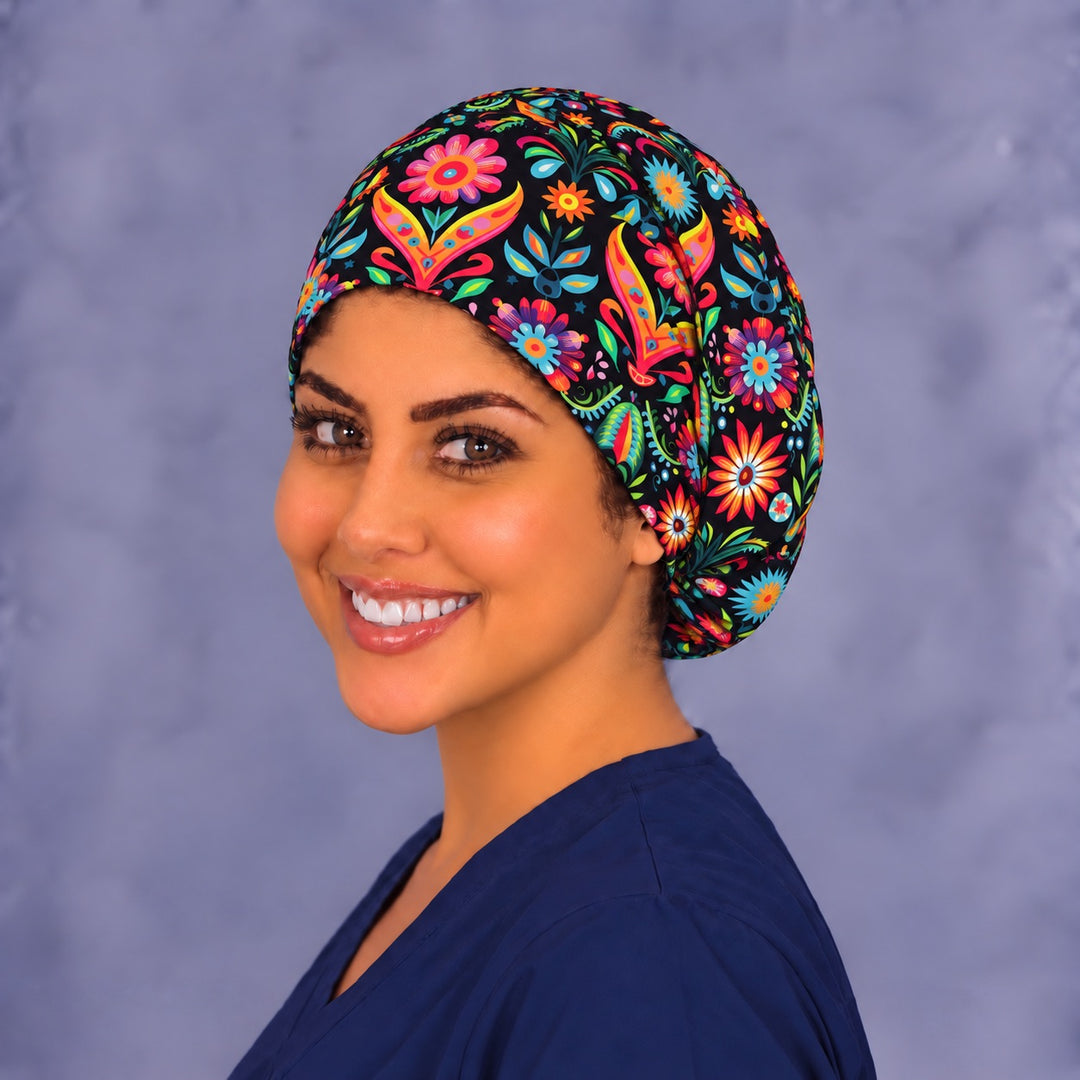 Angled portrait of a smiling healthcare worker in a Hispanic heritage euro scrub hat, with hot pink and orange blooms wrapping around the side of the cap