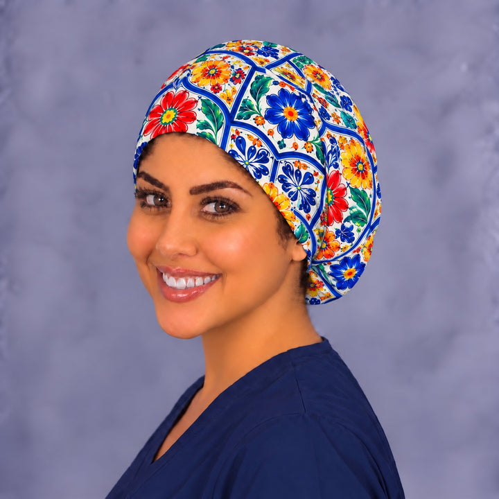 Left three-quarter angle of a smiling woman in a Hispanic heritage Euro scrub hat, showing blue and yellow tile flowers across the front and side