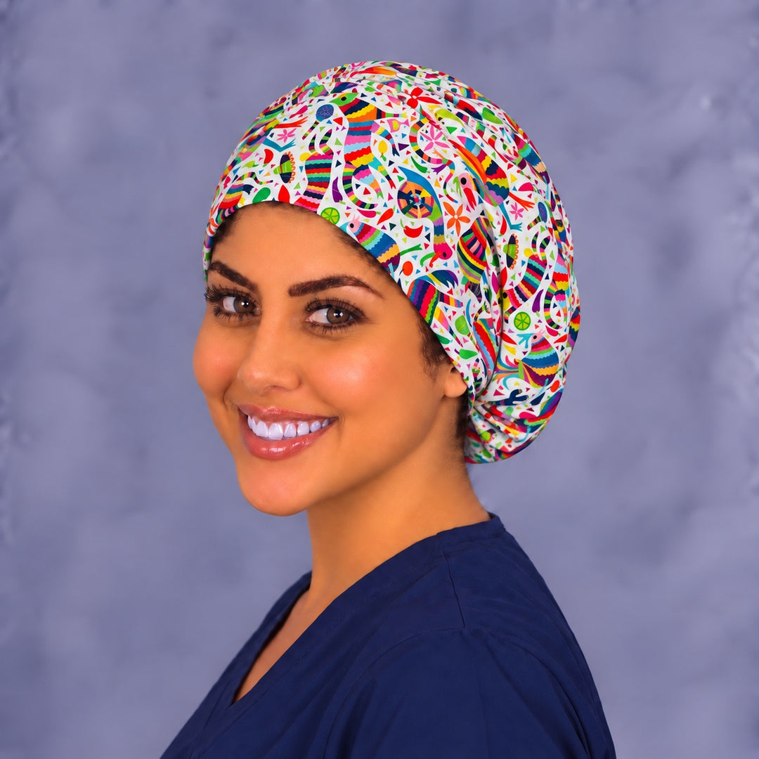 Left three-quarter angle of a smiling healthcare worker in a Hispanic heritage piñata scrub hat, showing the dense confetti scatter and print scale on the side