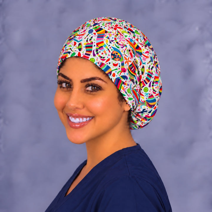 Left three-quarter angle of a smiling healthcare worker in a Hispanic heritage piñata scrub hat, showing the dense confetti scatter and print scale on the side
