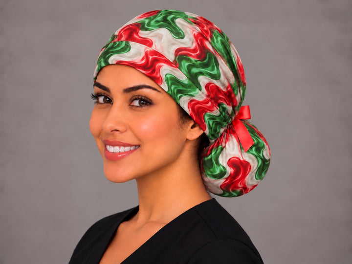 Left three-quarter angle of a smiling woman in a Hispanic heritage ponytail scrub hat, with wavy red and green stripes running across the band