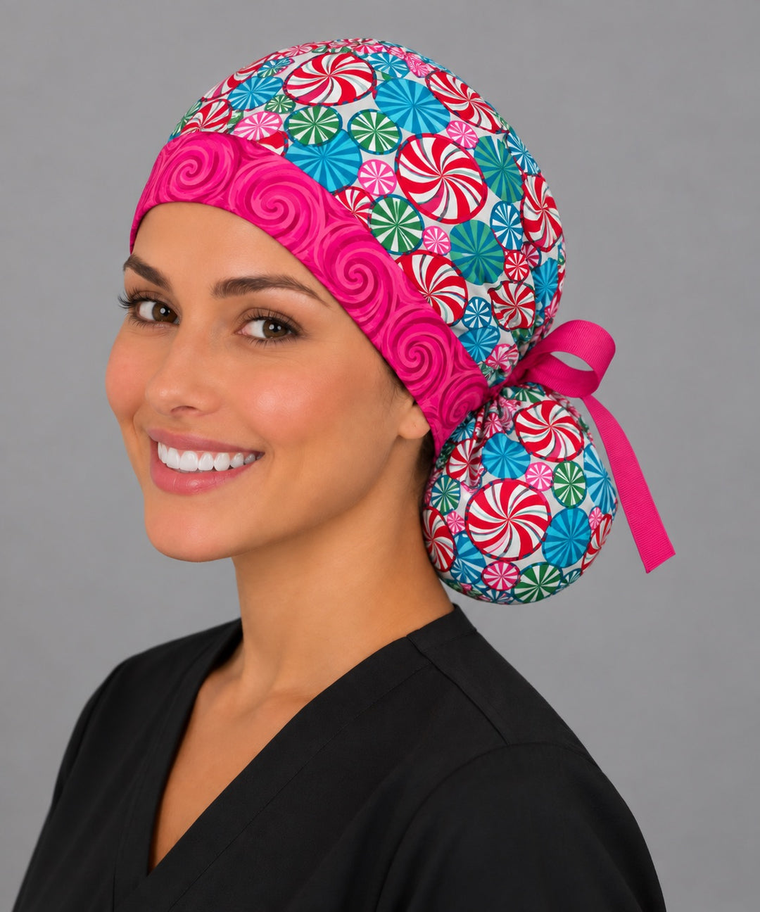 Holiday peppermint ponytail cap, left angled smiling view — festive candy print for OR nurses and surgical techs
