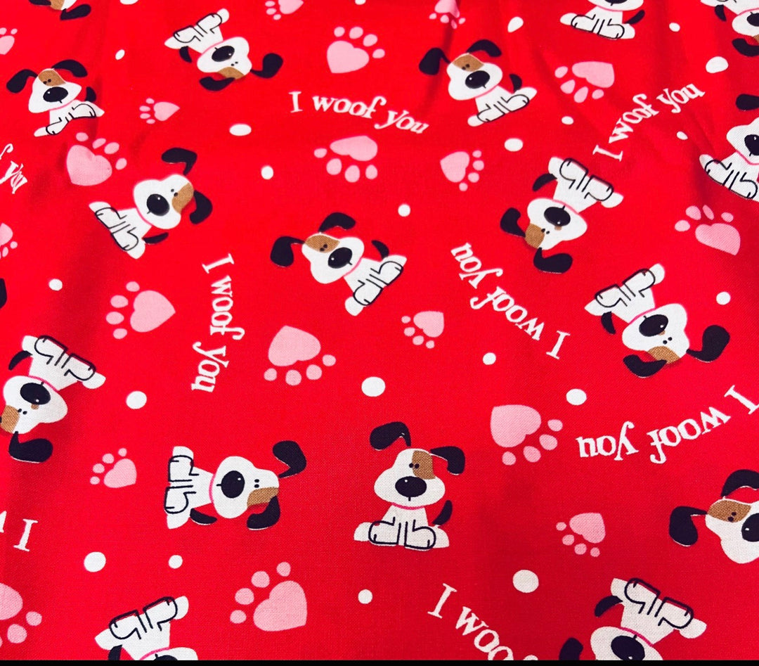 Fabric detail of the I Woof You scrub cap — close-up of red puppy, paw print and heart pattern