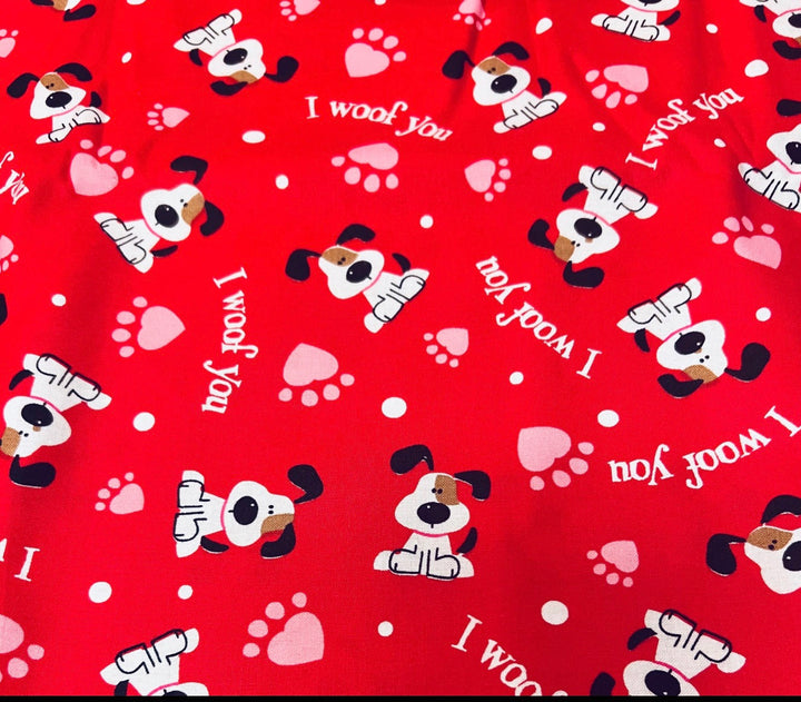 Fabric detail of the I Woof You scrub cap — close-up of red puppy, paw print and heart pattern