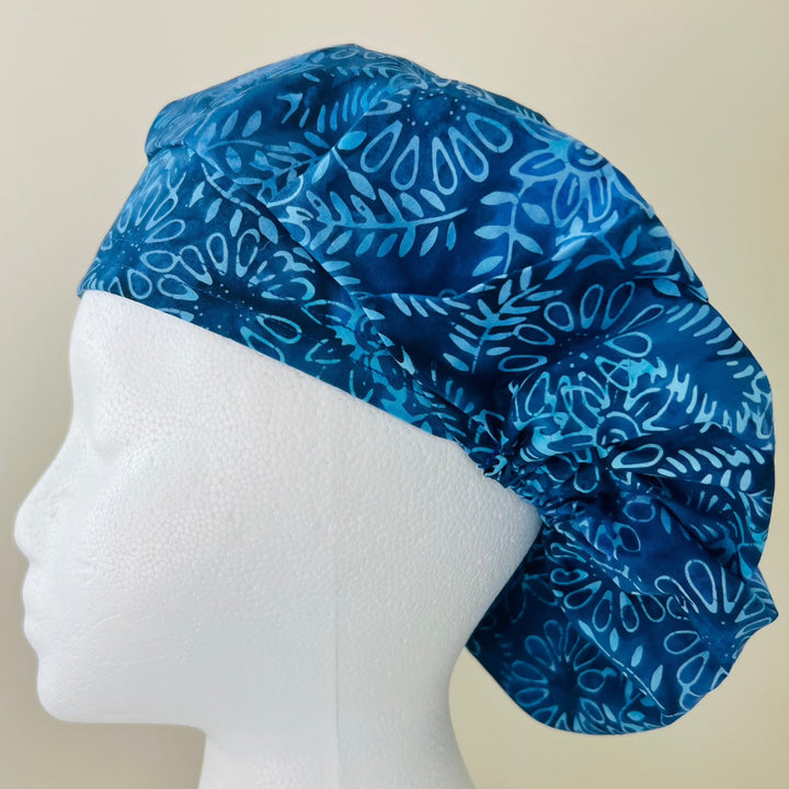 Side view of indigo blue floral batik bouffant scrub cap — handmade USA surgical hat for OR nurses with room for long hair.