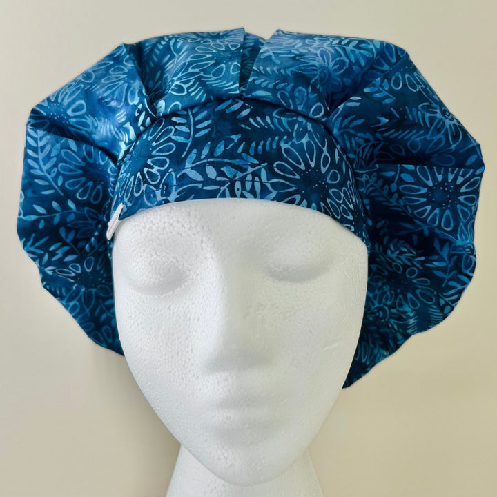 Side view of indigo blue floral bouffant scrub cap with room for long hair — handmade-in-USA OR World surgical hat for women.