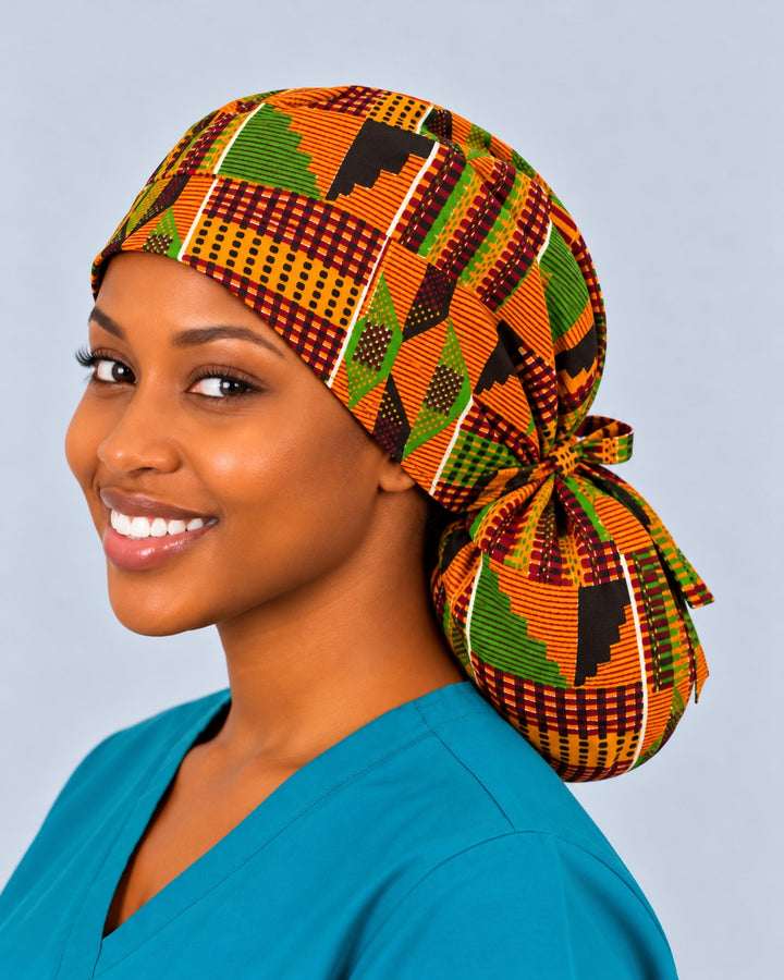 Left three-quarter view of a Kente print ponytail scrub cap for natural hair, with the fabric bow knot tied at the nape above the full pouch