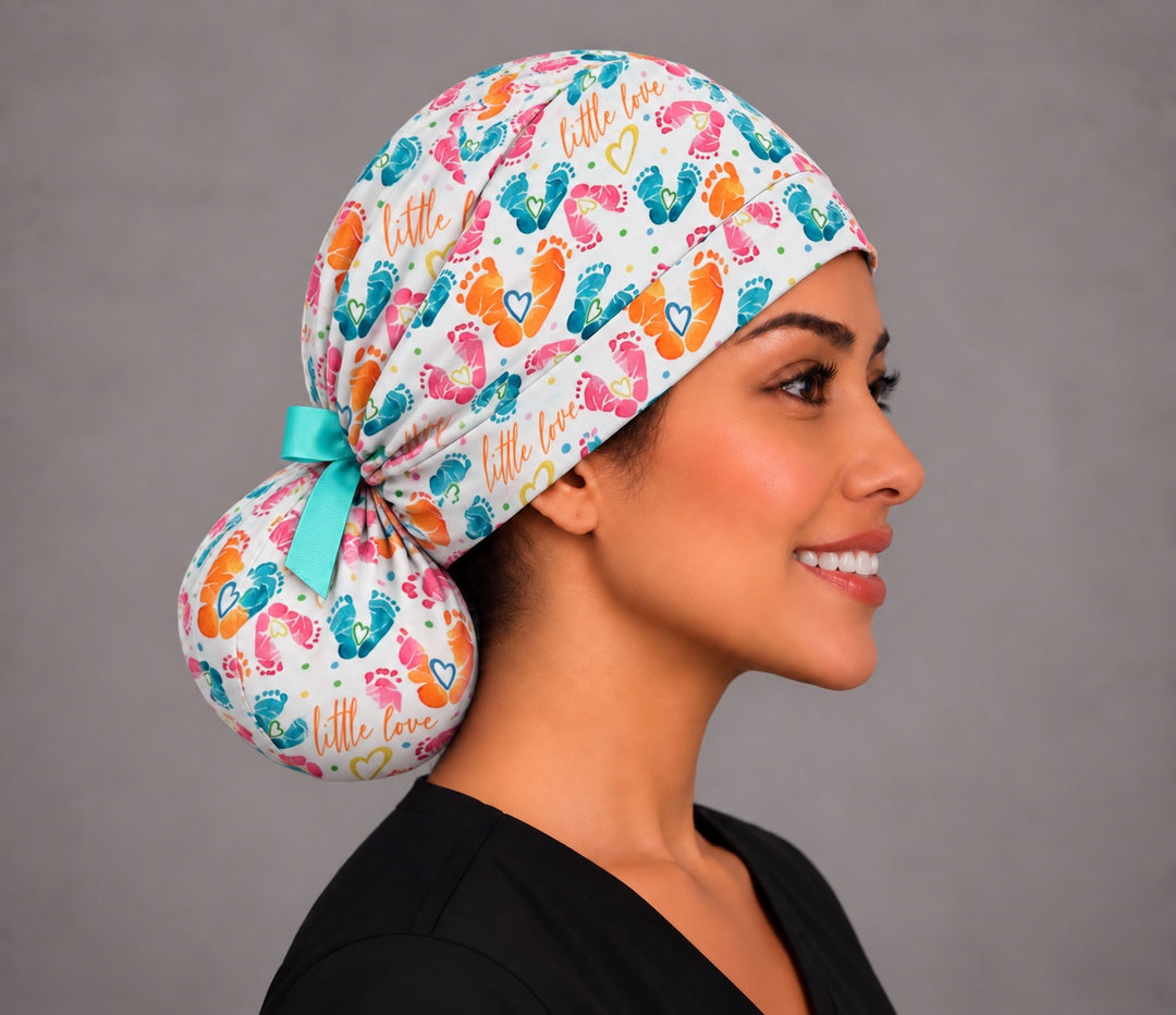 Right profile of a labor and delivery ponytail surgical hat, showing the aqua grosgrain bow tied above a full round ponytail pouch at the nape