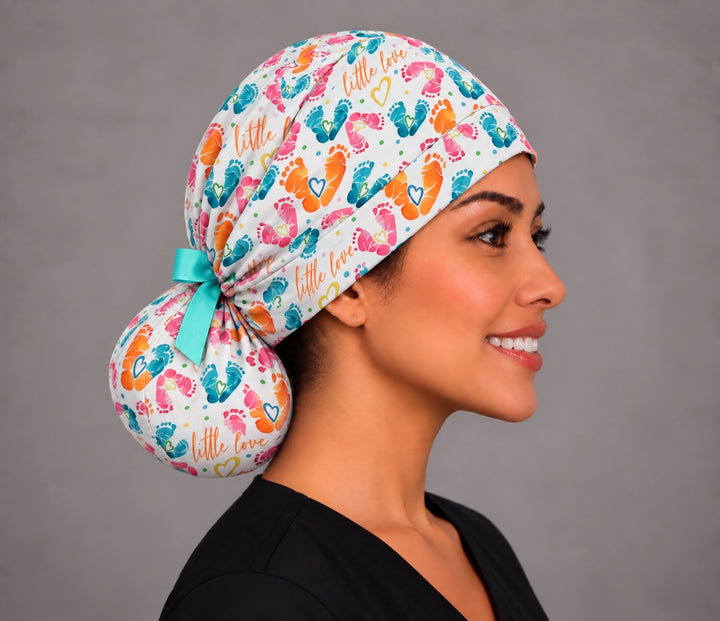 Right profile of a labor and delivery ponytail surgical hat, showing the aqua grosgrain bow tied above a full round ponytail pouch at the nape
