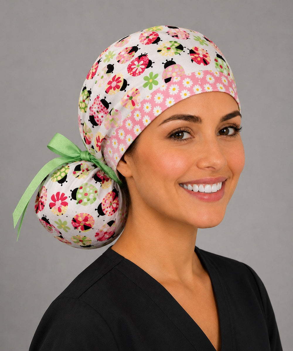 Ladybug daisy ponytail nurse cap right three-quarter angle on smiling model showing colorful ladybugs, daisies, pink band and green ribbon bow