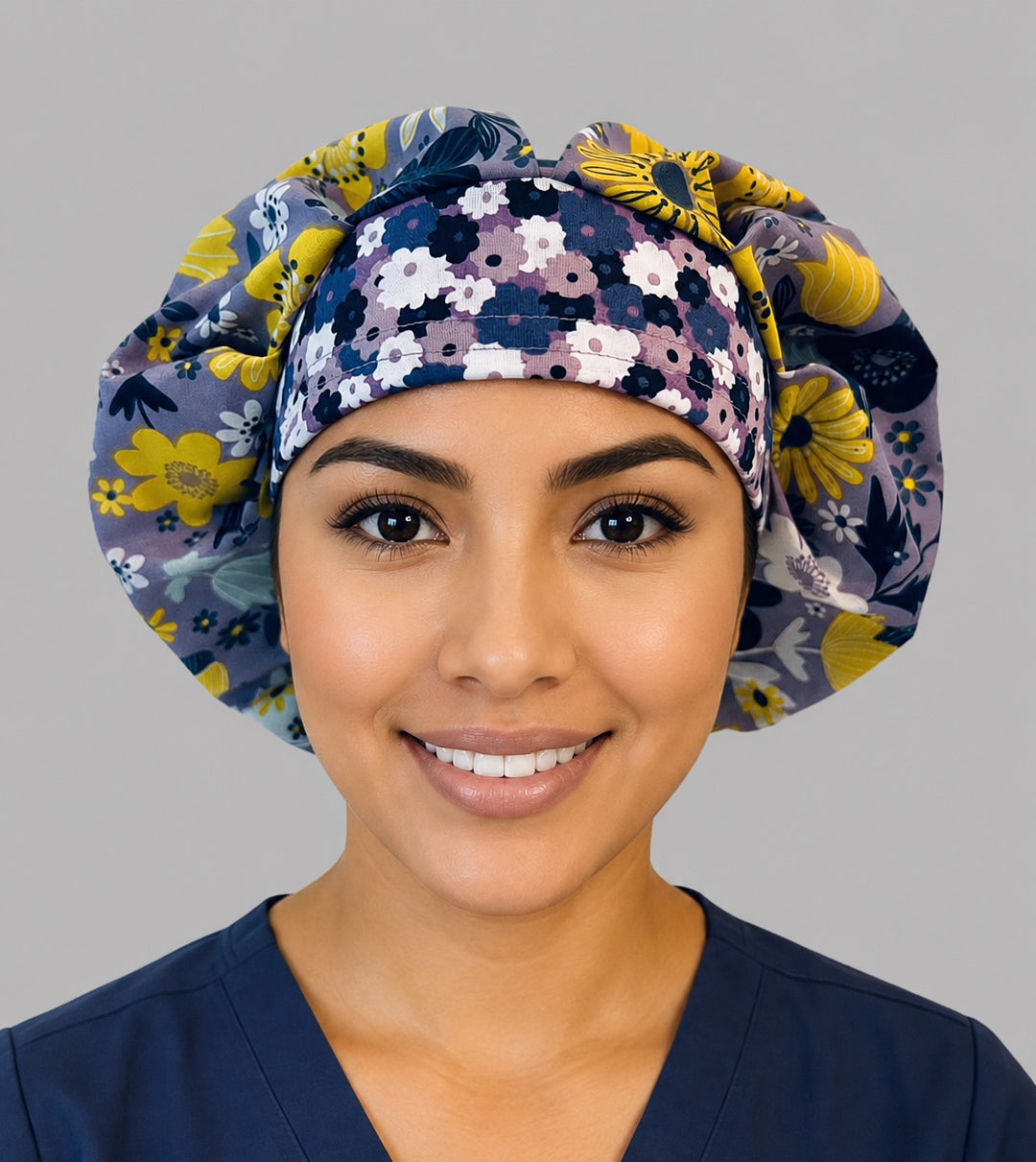 Woman wearing a lavender floral bouffant scrub cap, front view — yellow flowers, white daisies and navy accents on soft purple, adjustable women&