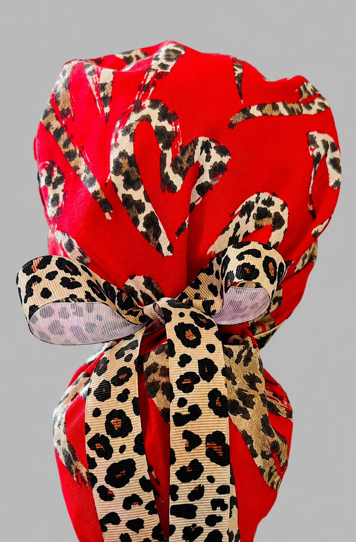Leopard print hearts ponytail scrub cap back close-up showing gathered pouch of leopard-print hearts on red with leopard-print grosgrain ribbon bow tie