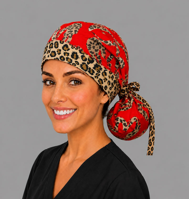 Leopard print hearts ponytail nurse cap left three-quarter angle on smiling model showing leopard-print hearts on red with cheetah band and animal-print ribbon bow