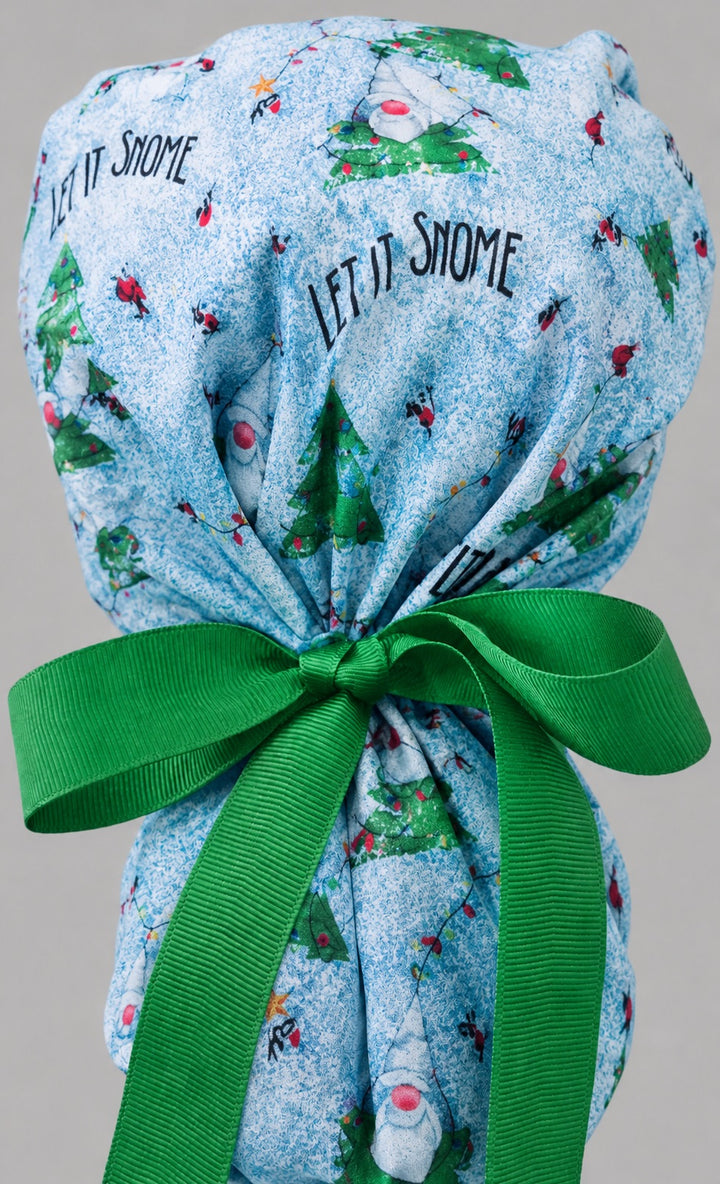 Let it Snome Christmas gnomes ponytail nurse cap left three-quarter angle on smiling model showing tree-gnomes, cardinals and green snowball band with green ribbon bow