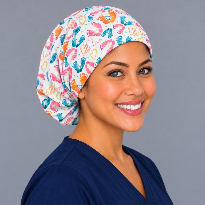 Right three-quarter angle of a Little Love OB nurse scrub hat, showing orange baby footprints with blue hearts across the crown and soft folds at the back