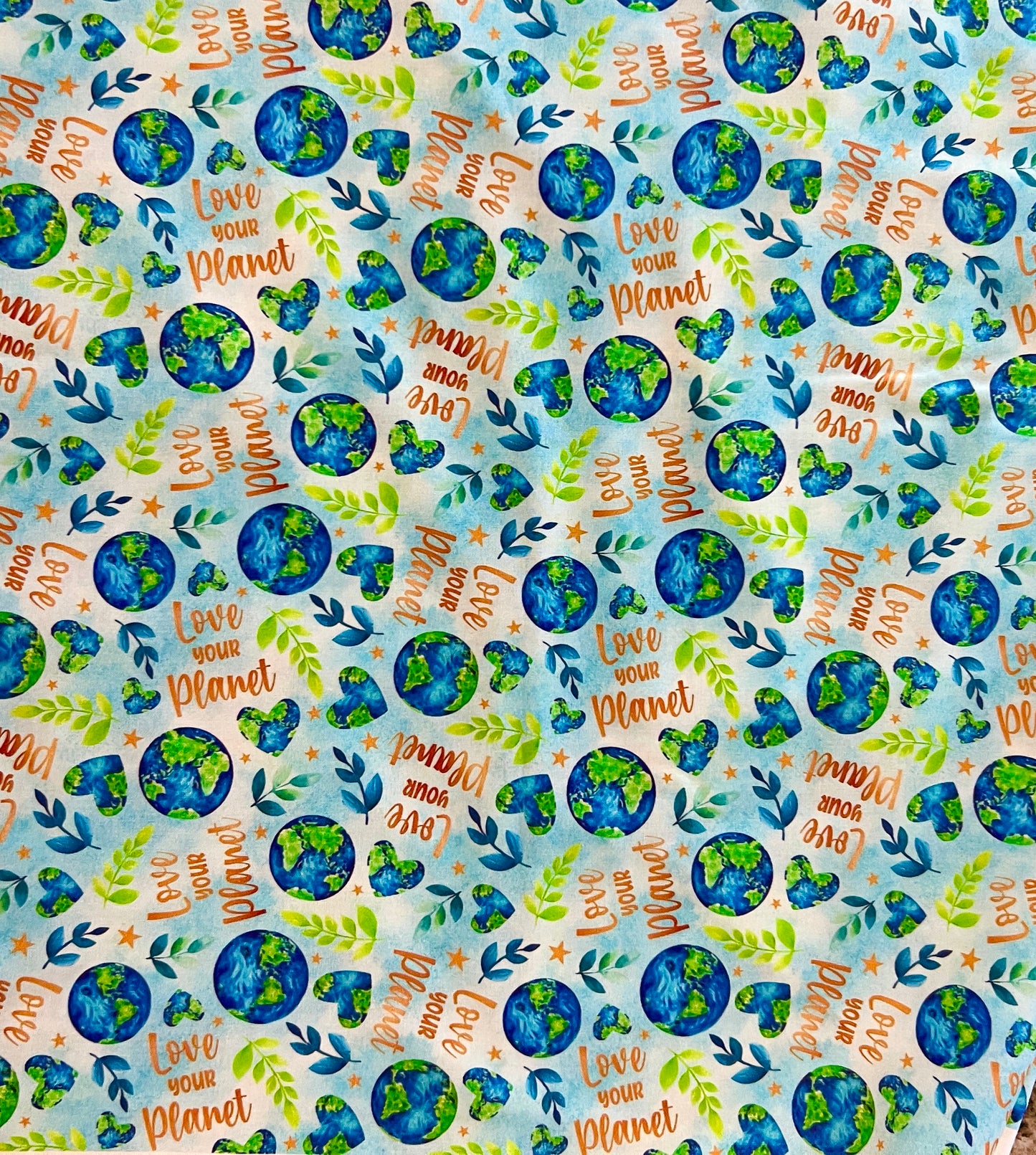 Love Your Planet fabric print swatch, watercolor Earth globes, green sprigs, and Love Your Planet lettering for OR World handmade scrub caps.
