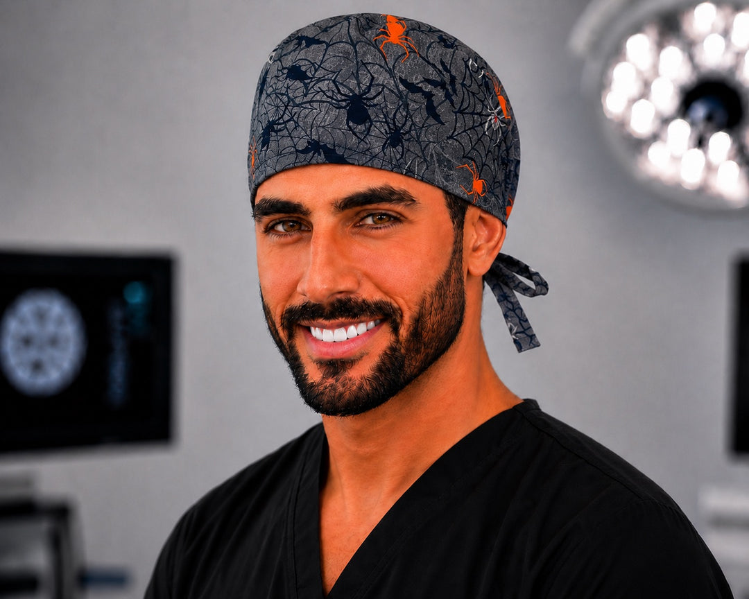 Man wearing OR World Halloween spider tie-back scrub cap, charcoal print with orange spiders, smiling front view