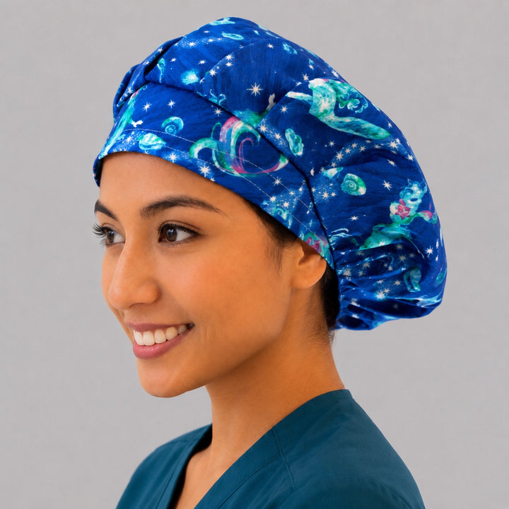 Mermaid ocean galaxy bouffant scrub cap left side profile showing glowing mermaids, shells and stars on deep blue sea, OR World surgical hat