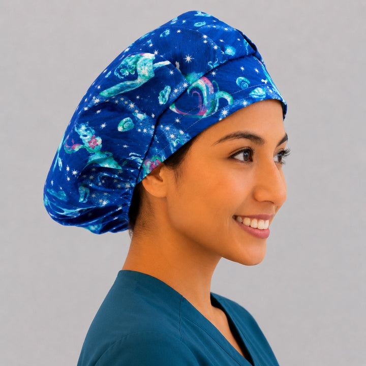 Mermaid ocean galaxy bouffant scrub cap right side profile showing glowing mermaids and stars on starry blue sea, women&