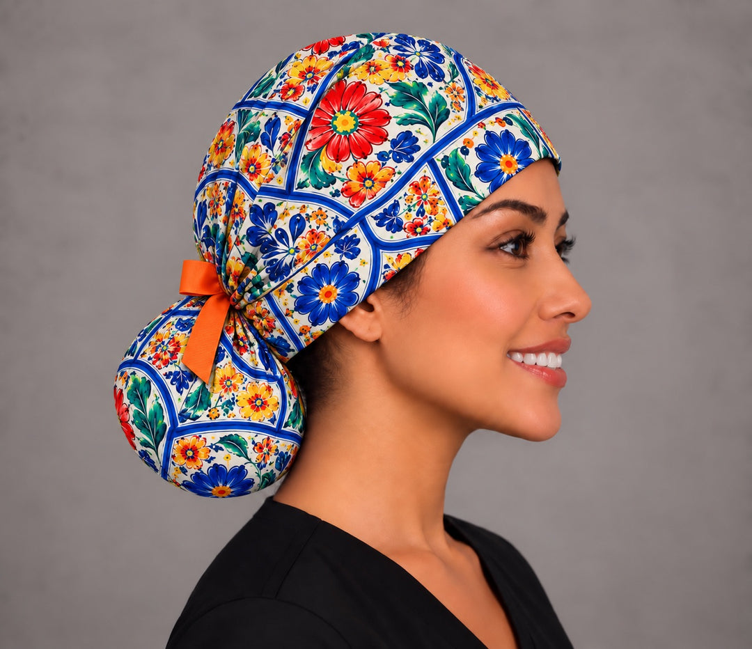 Right profile of a Mexican floral ponytail surgical hat for women, showing the rounded pouch at the nape cinched with an orange grosgrain ribbon