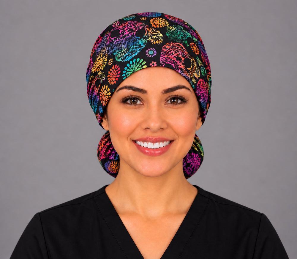 Nurse wearing a Mexican rainbow calavera ponytail surgical hat, front view, filigree sugar skulls and flower bursts on black
