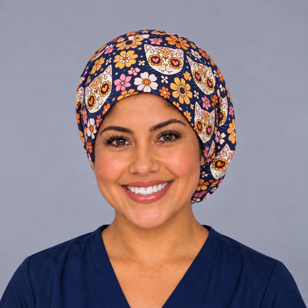 Nurse wearing the Fiesta Gato Mexican scrub cap, front view, navy Euro surgical hat with heart-eyed sugar skull cats and marigold flowers
