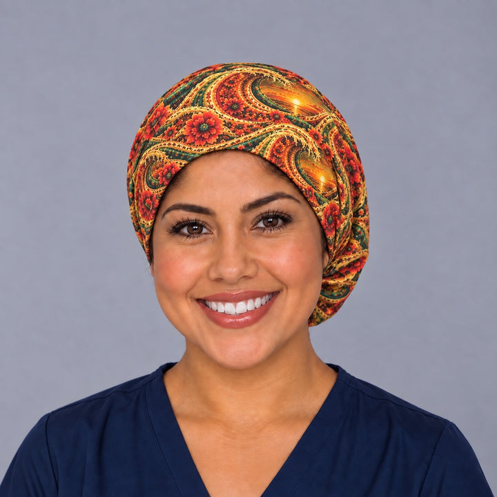 Woman wearing a Mexican sunset Euro scrub cap, front view — gold waves, orange sunsets and red dahlias, adjustable surgical hat