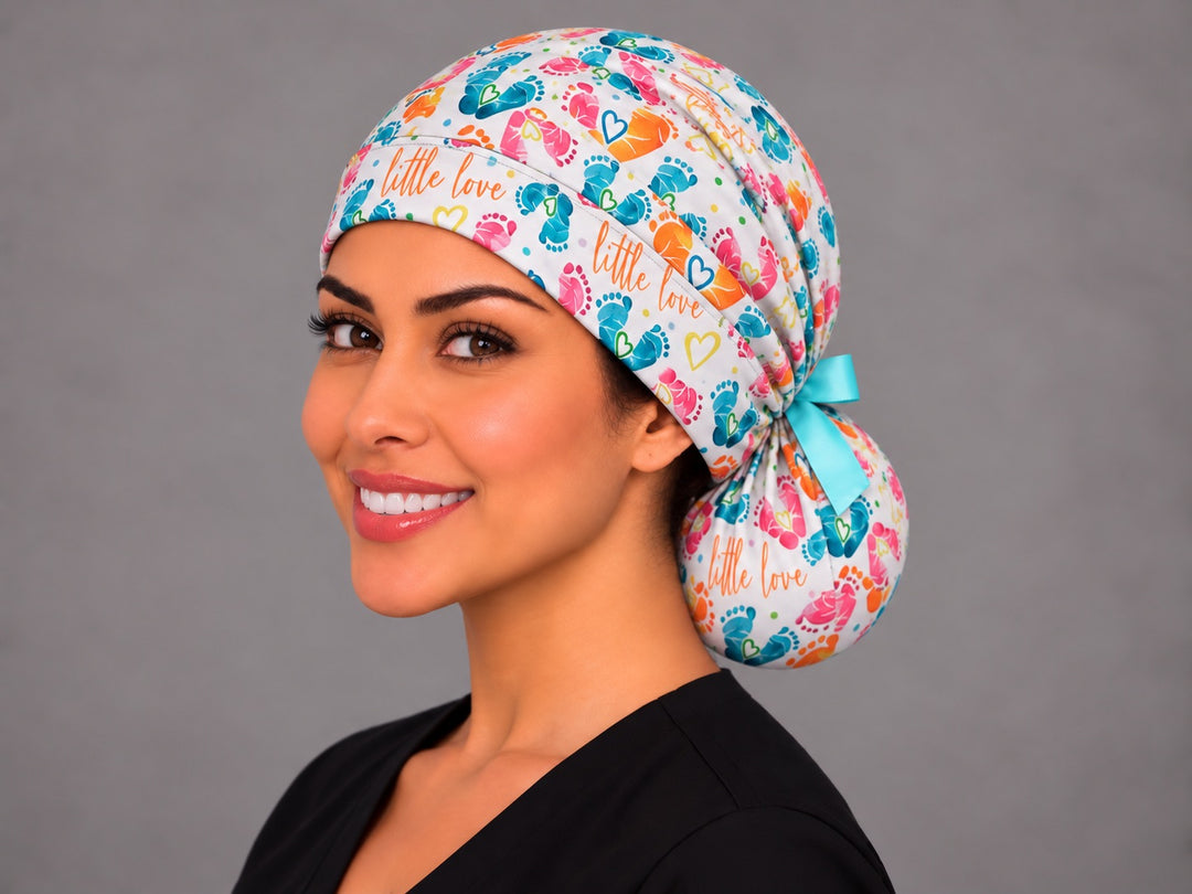 Left three-quarter angle of a smiling midwife in a ponytail scrub cap, with yellow outline hearts and confetti dots along the band at true print scale