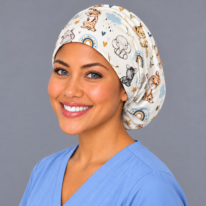 Left three-quarter angle of a smiling midwife in a nursery animal scrub cap, with a baby hippo and lion cub at true print scale along the band