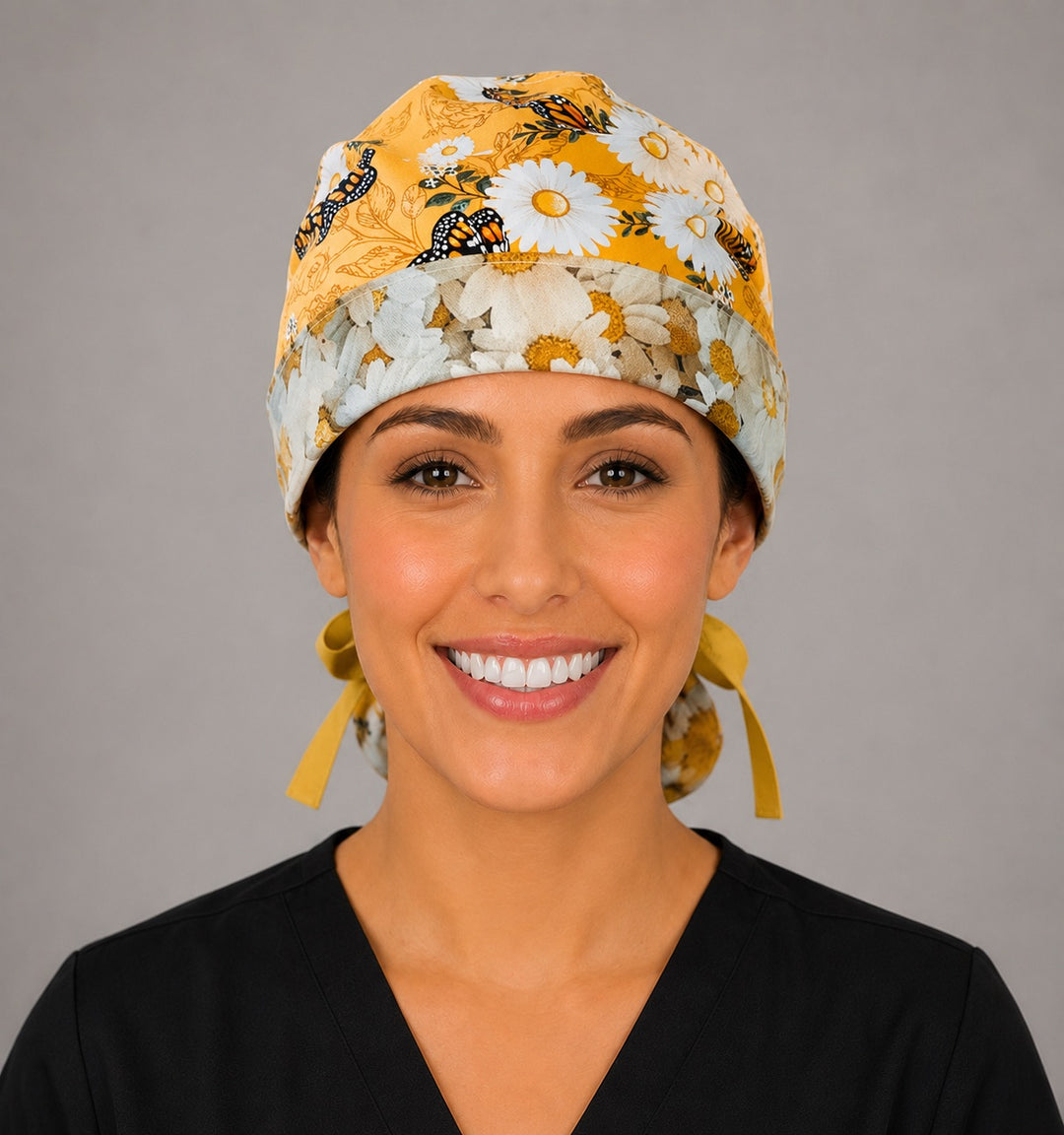 Monarch butterfly daisy ponytail nurse cap left three-quarter angle on smiling model showing orange monarchs, white daisies and white ribbon bow