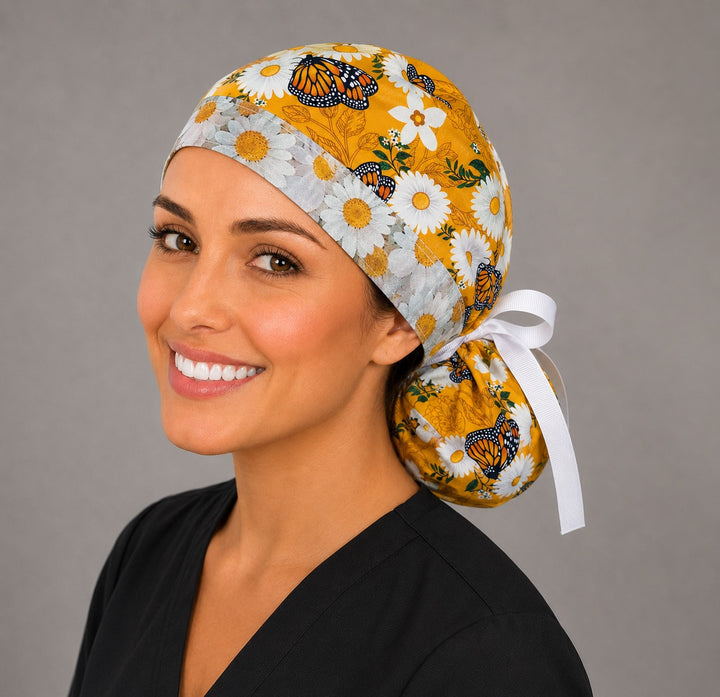 Monarch butterfly daisy ponytail scrub cap right three-quarter angle showing orange monarchs, white daisies on golden yellow with daisy accent band