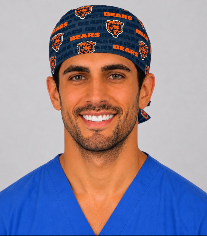 Male surgeon in royal blue scrubs wearing a navy and orange football print tie-back scrub cap, front view showing the full crown and clean forehead band