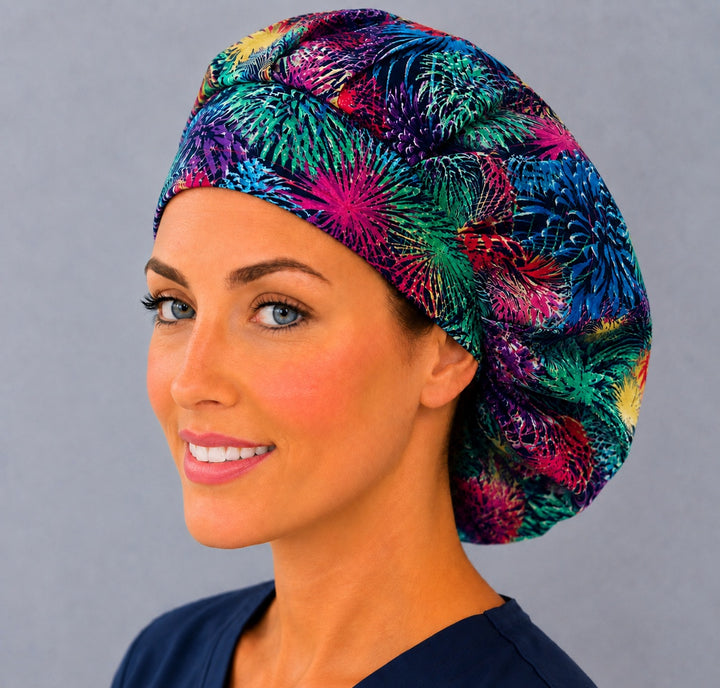 Neon firework bouffant scrub cap, left angled smiling view — bright starburst print for OR nurses and surgical techs