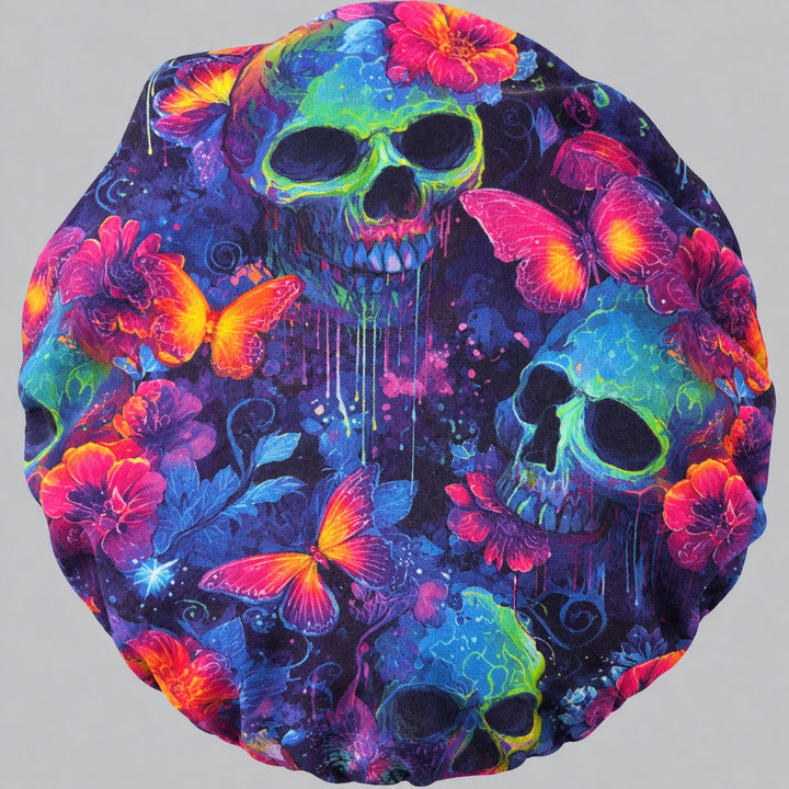 Neon Skull &amp; Butterfly bouffant scrub cap, flat lay view — glowing skulls, pink butterflies and flowers on indigo fabric