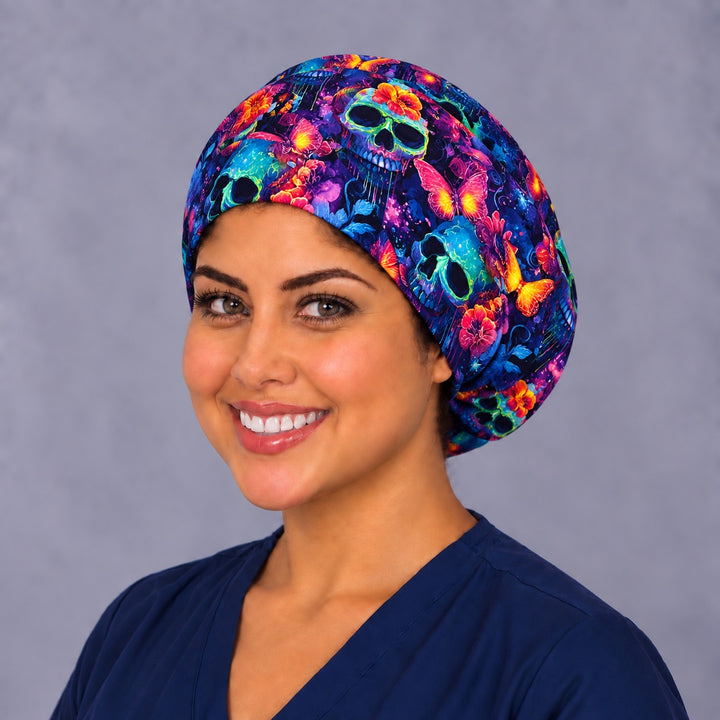 Neon sugar skull Euro scrub cap, left three-quarter view, Mexican Día de los Muertos surgical hat with glowing teal calaveras and pink butterflies