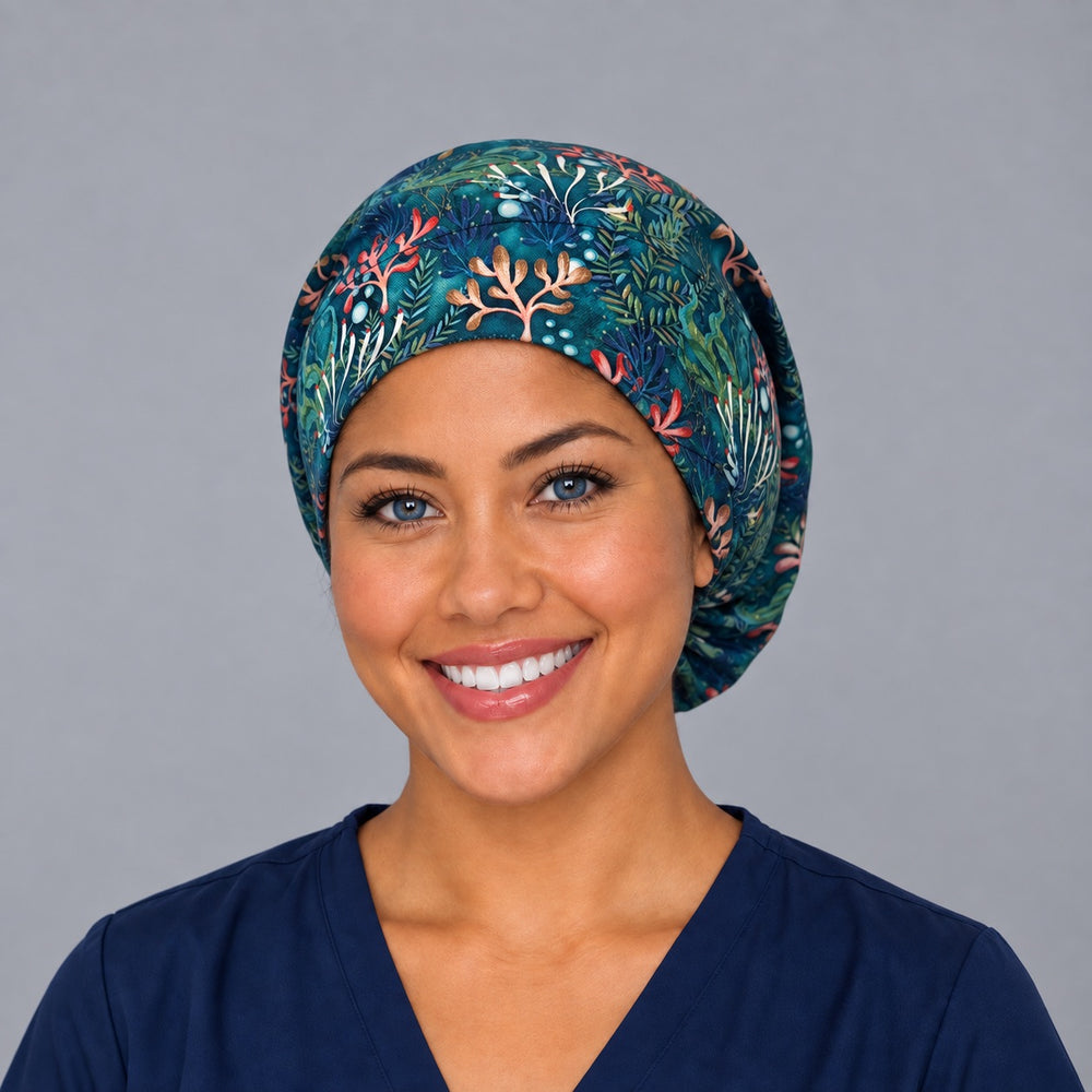 Woman wearing an ocean coral reef Euro scrub cap, front view — coral and kelp on deep teal, adjustable surgical hat for nurses