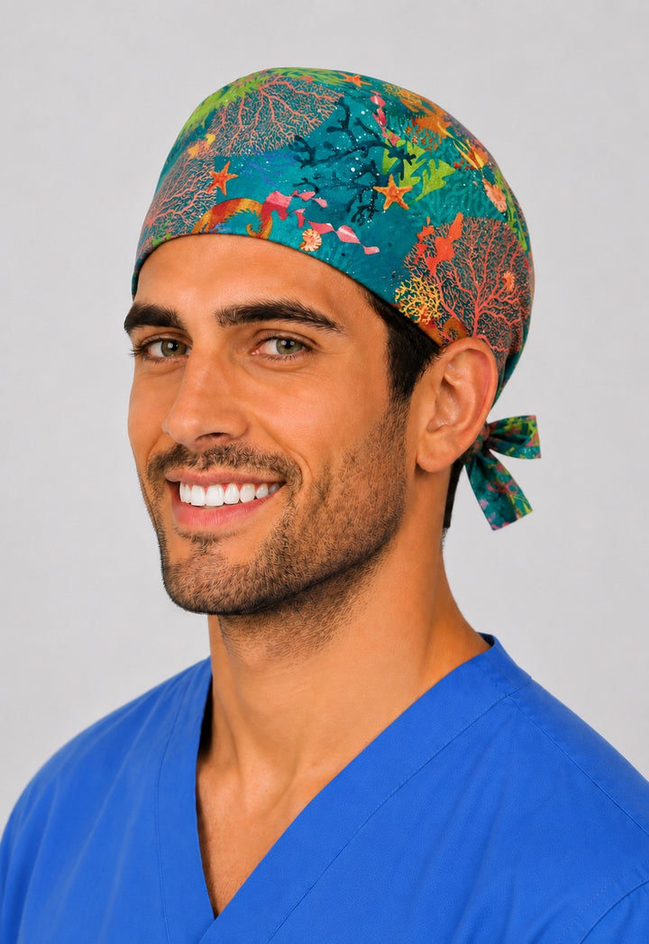 Ocean coral reef tie back scrub cap, front three quarter view on a smiling male nurse in blue scrubs, colorful sea life and seahorse marine theme surgical hat, handmade in USA by OR World.