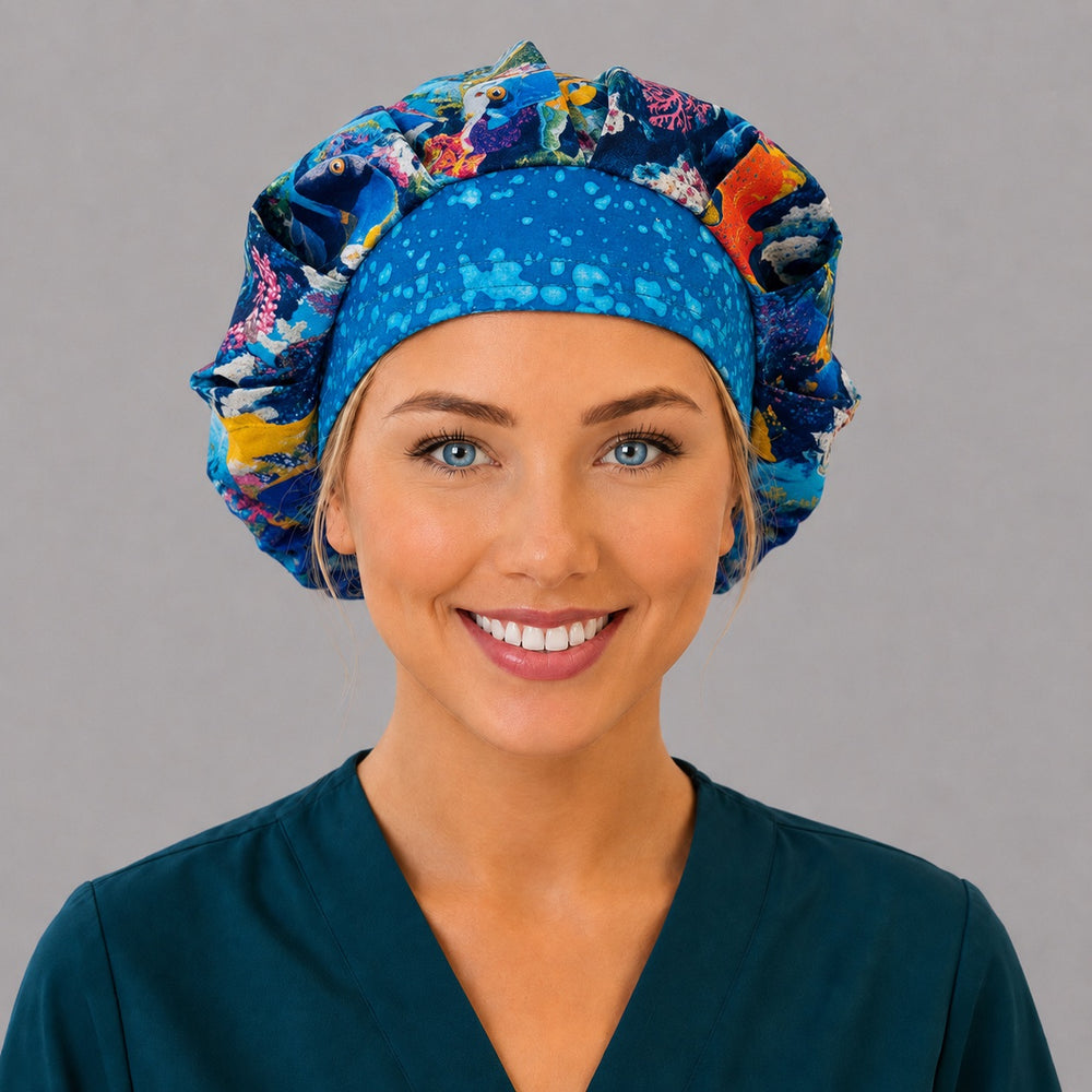 Woman wearing an ocean fish bouffant scrub cap, front view — tropical reef fish with a blue bubble band, adjustable women's surgical hat