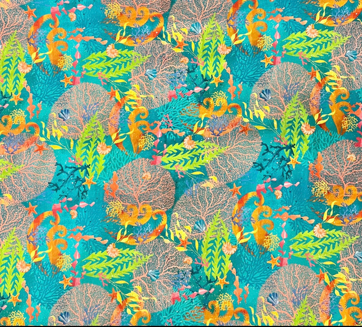 Fabric detail of the ocean reef scrub cap — close-up of seahorses, kelp fronds, starfish and shells on teal batik cotton