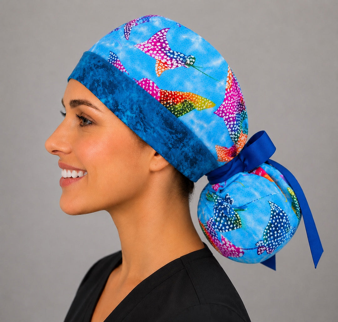 Ocean stingray ponytail scrub cap left side profile with full ponytail pouch of colorful stingrays on blue water and long navy ribbon ties