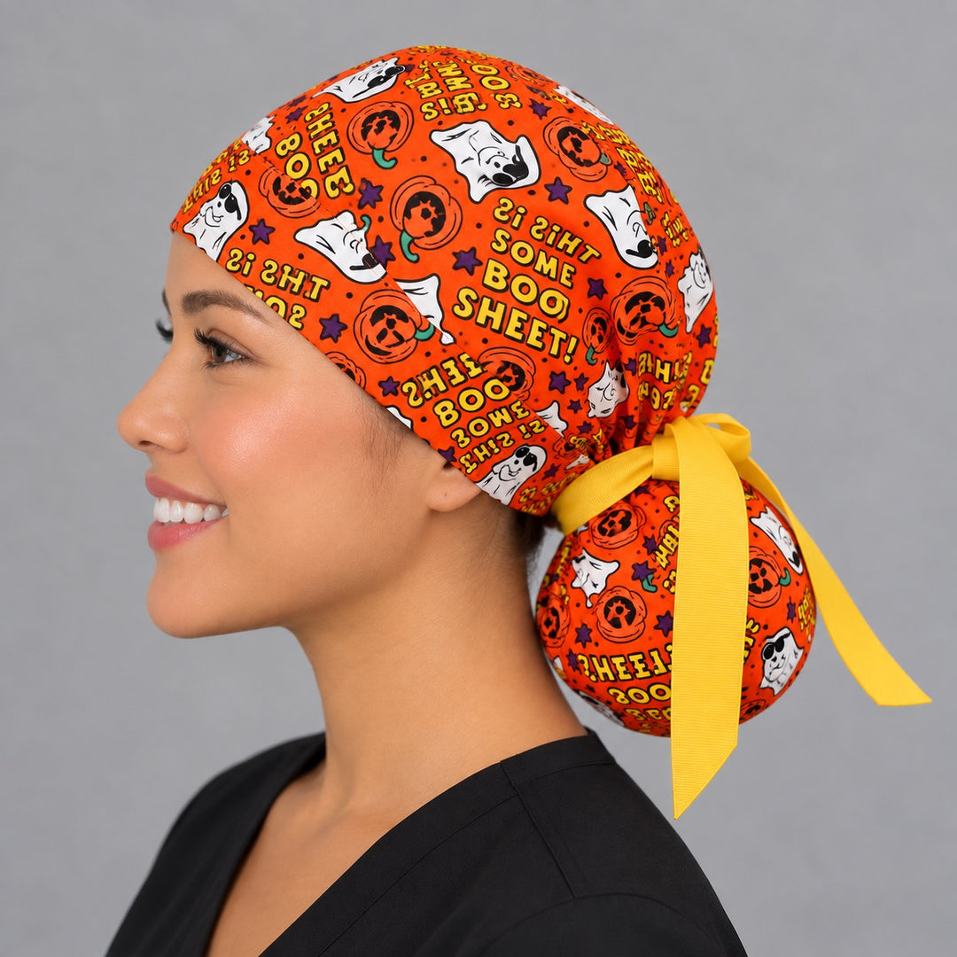 Orange pumpkin and ghost ponytail surgical cap, left side profile — deep pouch that holds long thick or braided hair securely