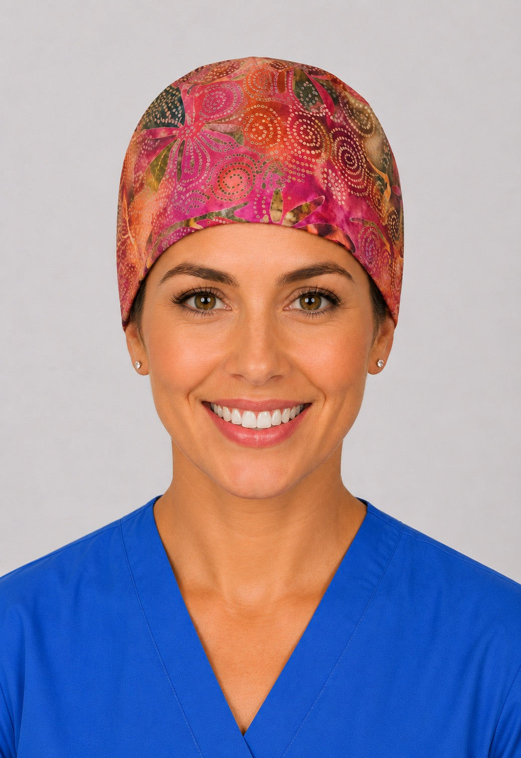 Nurse wearing orange sunset batik tie back scrub cap, front view of hand dyed surgical hat for short hair by OR World