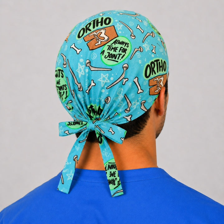 Back view of the orthopedic We Do Joints tie-back scrub cap showing the bow tie closure and full bone print