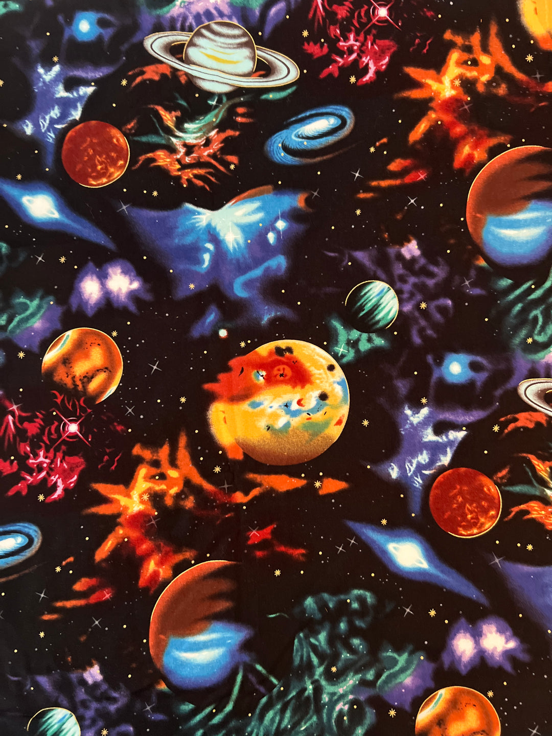 Detailed fabric print of outer space scrub cap with swirling galaxies, gold stars, and multicolor planets on black cotton