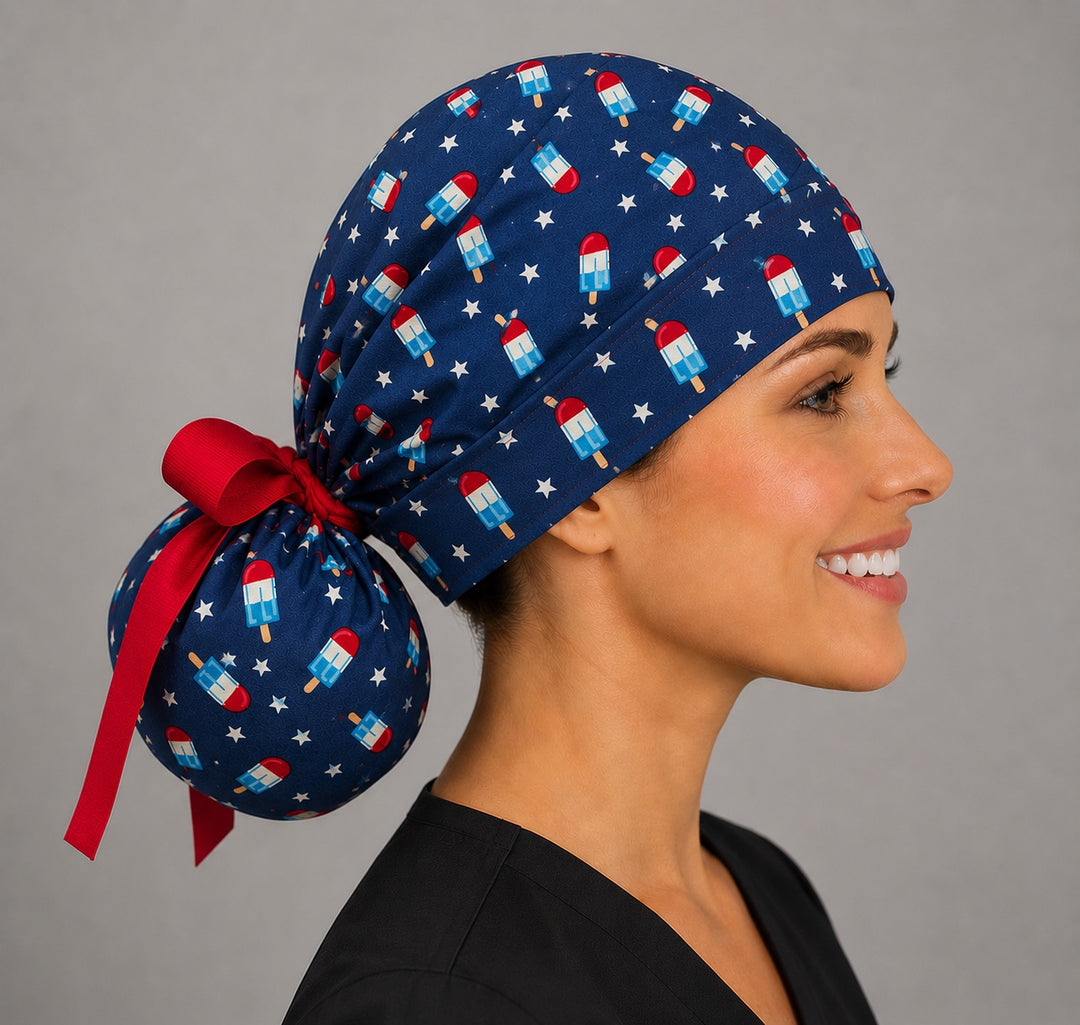 Patriotic popsicle ponytail scrub cap left side profile with full ponytail pouch of red white blue popsicles, stars and long red ribbon ties