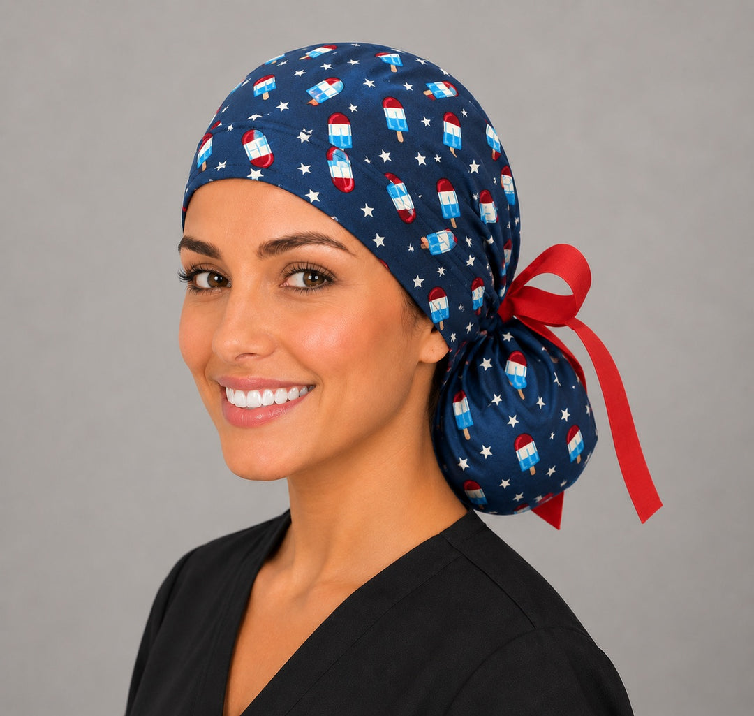 Patriotic popsicle ponytail nurse cap right three-quarter angle on smiling model showing red white blue popsicles, stars and red grosgrain ribbon bow