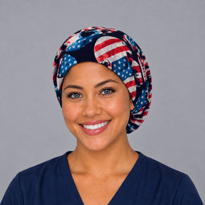 Woman wearing a patriotic skull Euro scrub cap, front view — American flag skulls on black, adjustable red white and blue surgical hat