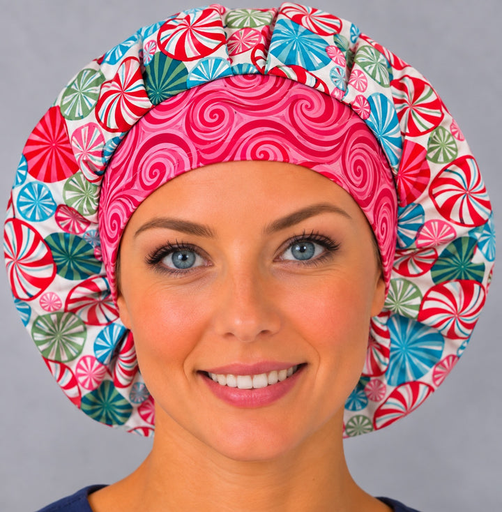 Woman wearing a peppermint swirl bouffant scrub cap, front view — red, teal and pink candy swirls with a pink swirl band, adjustable women&