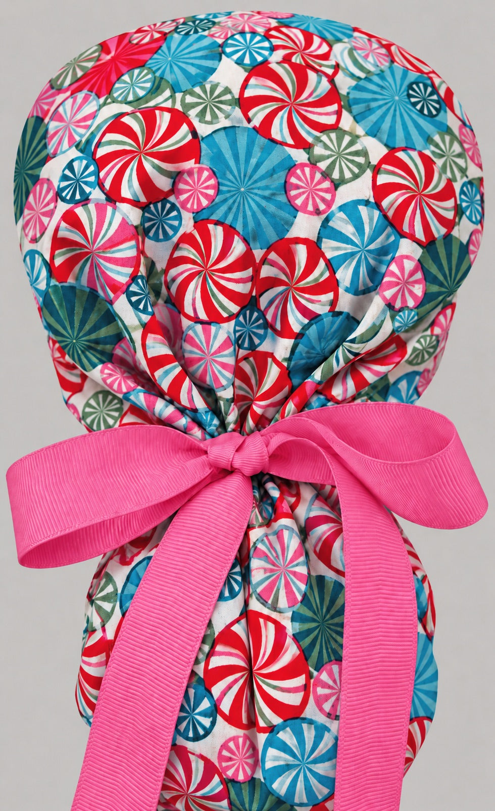 Back view of the peppermint ponytail scrub cap — full candy print with pink grosgrain bow tie on the pony pouch